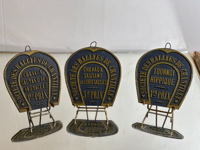 trois plaques métalliques représentant un fer à cheval et un fer à cheval posé sur une table