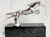 statue d'un cheval posée sur un socle en marbre, sur fond blanc
