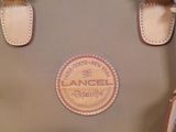 tan and brown handbag with leather handles on a blue surface