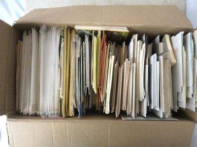 une boîte en carton remplie de dossiers et de papiers posée sur un lit