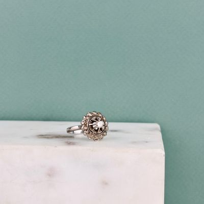 un gros plan d'une bague en argent posée sur un bloc de marbre