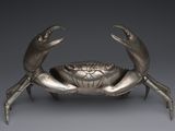une image représentant une statue de crabe argentée sur fond gris