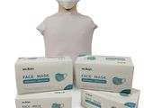 une personne portant un masque à côté de trois boîtes de masques