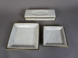 trois assiettes blanches aux bords dorés sont posées sur une table