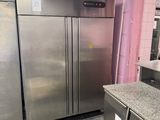 stainless steel refrigerators and freezers in a kitchen with pink walls