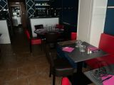 tables and chairs in a restaurant with a bar in the background