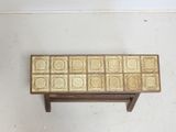a small wooden bench with a tile design on top of it