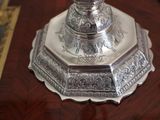 a silver vase on a wooden table with a mirror in the background