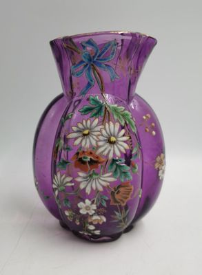 un vase violet orné de fleurs, posé sur une table