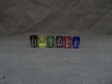 plusieurs verres à shot de différentes couleurs alignés sur une surface grise