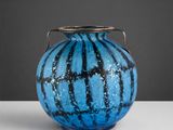 un vase bleu posé sur une table, muni d'une anse en argent