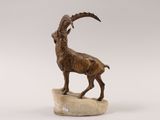 statue of a goat standing on a rock on a white background