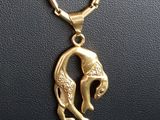 a close up of a gold necklace with a fish on it