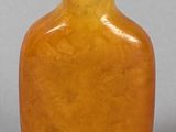 yellow glass snuff bottle with a tiger eye on the top
