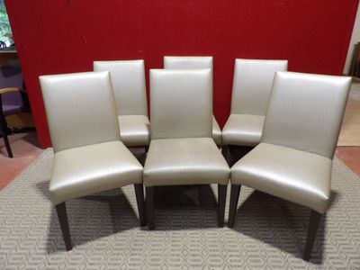 six chaises de salle à manger en cuir crème dans une pièce dont l'un des murs est rouge