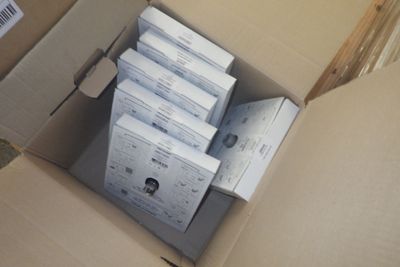 une boîte en carton remplie de dossiers papier, posée par terre