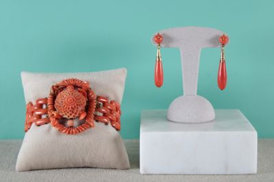 two pieces of jewelry sitting on top of a pillow next to a pillow
