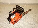 an orange chainsaw sitting on the floor in front of a wall