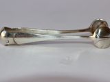 une cuillère en argent et un repose-cuillère posés sur une surface blanche