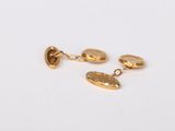 a close up of a pair of gold earrings on a white surface