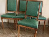 quatre fauteuils en cuir vert posés sur un parquet, près d'un mur