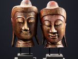 paire de têtes de Bouddha sculptées dans le bois, posées sur un socle en marbre