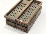 une petite boîte en bois percée de trous, posée sur une surface blanche