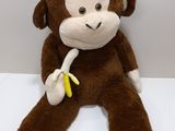 a stuffed monkey sitting on a shelf with a banana in it ' s hand