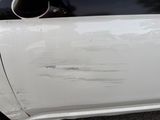 a close up of a white car with scratches on the door