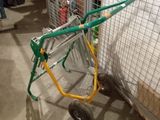 a green and yellow hand truck parked in front of a cage