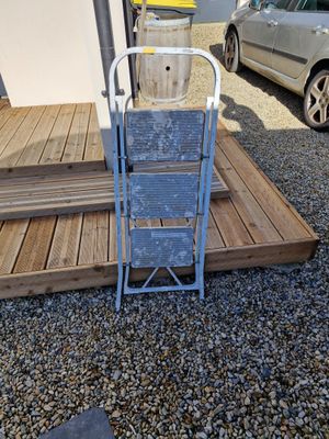 a ladder that is sitting on the ground next to a car