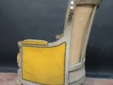 an old chair with a yellow upholstered seat on a pink carpet
