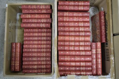 de nombreux livres rouges dans une boîte posée par terre