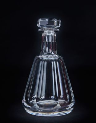 une image représentant une bouteille en verre transparent munie d'un bouchon, sur fond noir