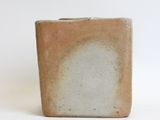 a brown and white square vase with a white background