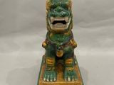une statuette foo foo verte et dorée posée sur une petite table
