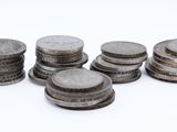 several stacks of coins sitting on top of each other on a white surface