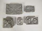 four metal molds of different shapes and sizes on a white surface