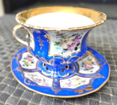 une tasse et une soucoupe posées sur une table où se trouve une bougie