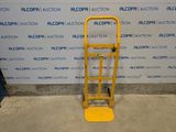 a yellow hand truck that is sitting in front of a wall