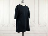 une robe noire posée sur un mannequin contre un mur blanc