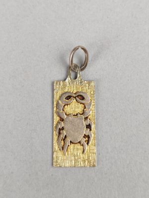 a silver and gold crab charm on a white background