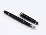 two black and gold fountain pens sitting on top of a white surface