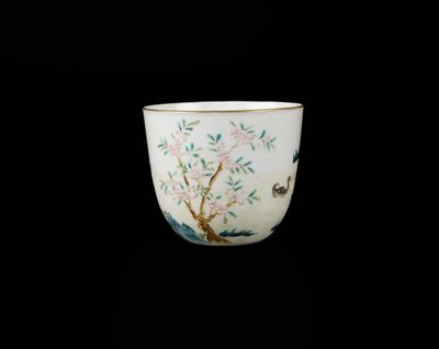 une tasse blanche sur laquelle sont peints un arbre et des oiseaux
