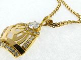 a close up of a gold necklace with a crown on it