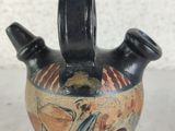 a black vase with a design on it sitting on a table