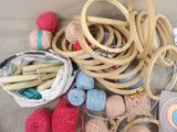 a basket full of yarn and knitting needles on a couch