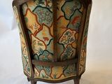 an upholstered chair with a floral upholstered back and wooden legs