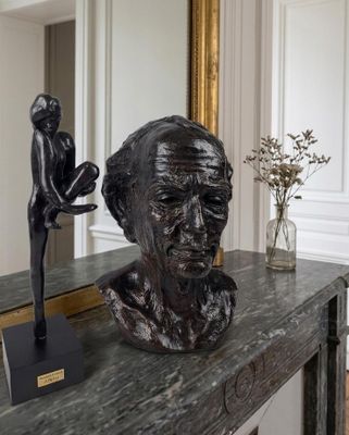 a statue of a man sitting on a table next to a vase of flowers