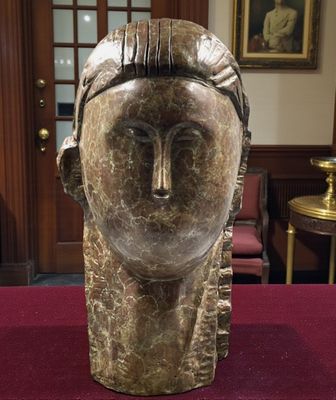 sculpture représentant la tête d'une femme posée sur une table dans une pièce